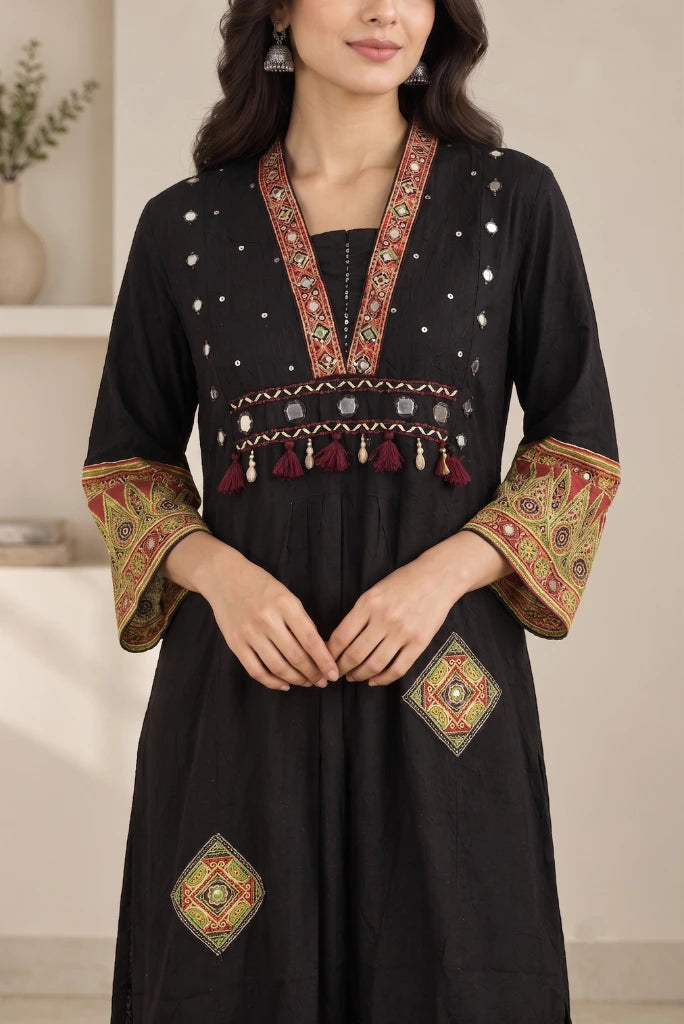 Close-up of black kurta V-neck with tassel yoke and mirror work
